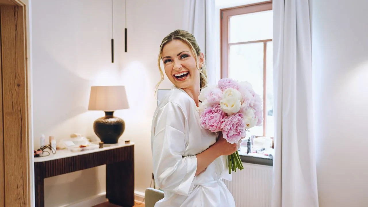 Gorgeous bride getting ready in a beautiful in a bathrobe with wedding flowers Gorgeous bride getting ready in a beautiful in a bathrobe with wedding flowers